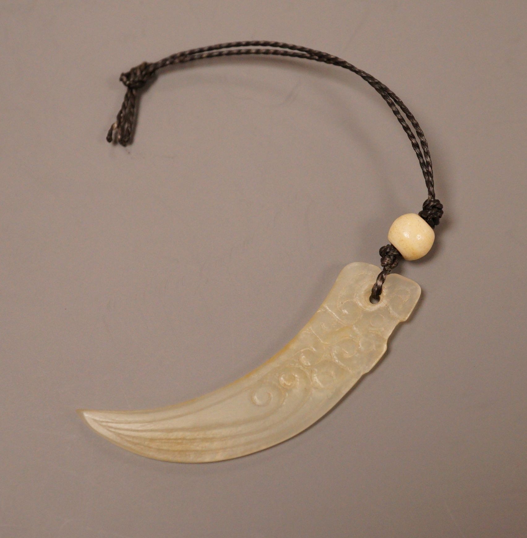 A Chinese jade tooth shaped pendant with bone bead